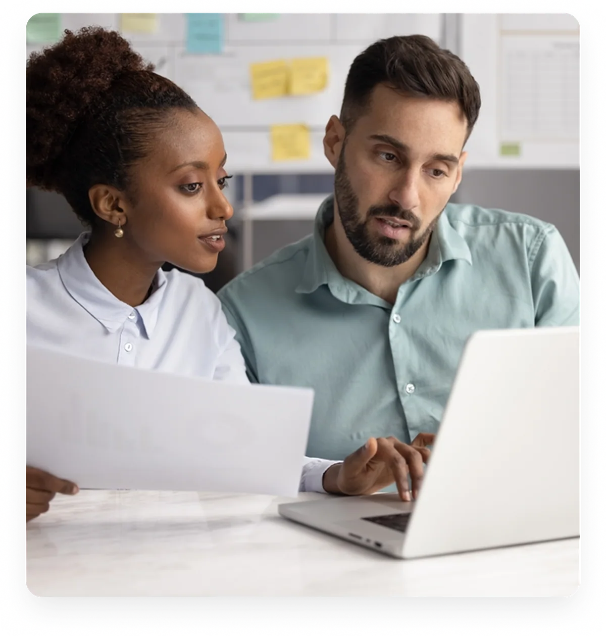 Two professionals collaborating while looking at a laptop in an office